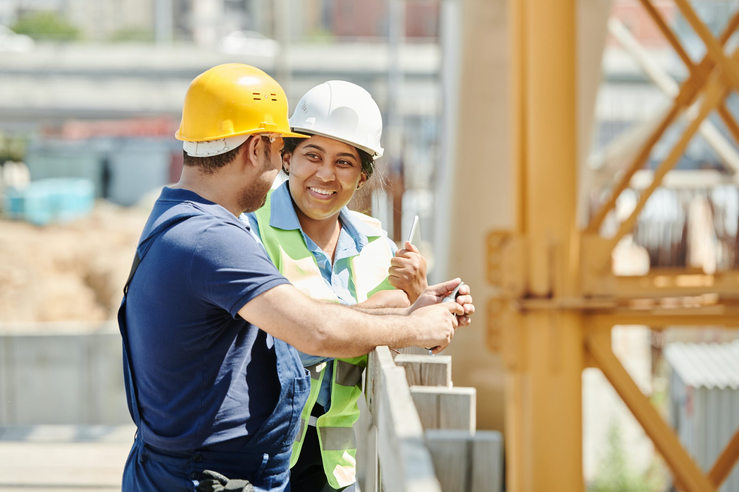 Man and woman talking on a construction site wearing hard hats